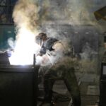 A skilled welder working with intense sparks and smoke in an industrial workshop, showcasing safety and precision.