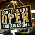 people inside building with come in we're open and awesome sign